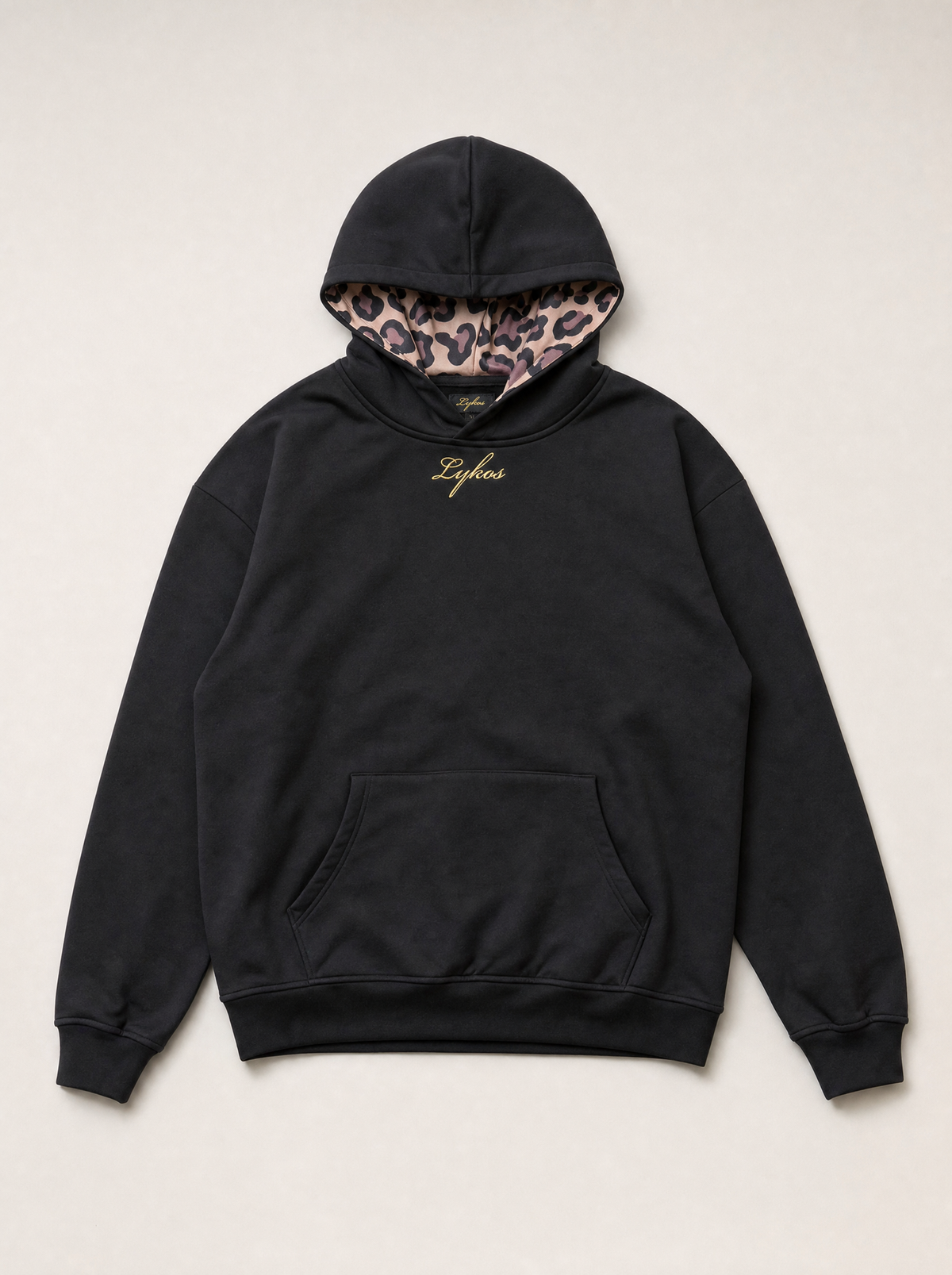 Origin Hoodie in black, front, laid flat, with gold Lykos embroidery and leopard-lined hood